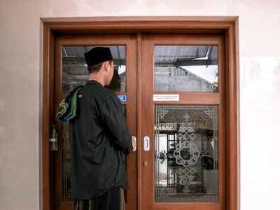 Stand in front of the brown wooden door man wearing a black jacket
